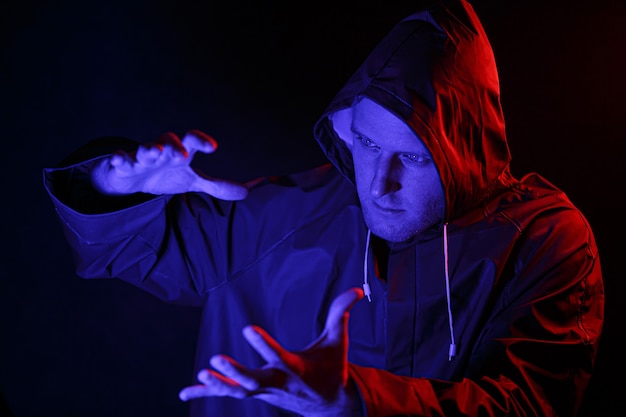 Un hombre con traje de protección en una habitación oscura. Concepto de imagen de Halloween. Protección de virus. Iluminado con luces de colores