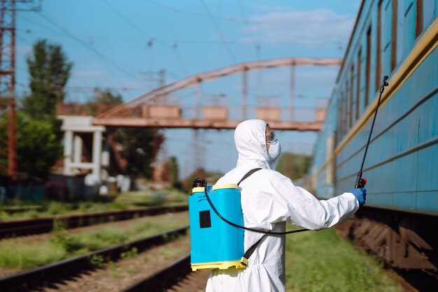 Hombre con traje protector desinfectando un tren público.