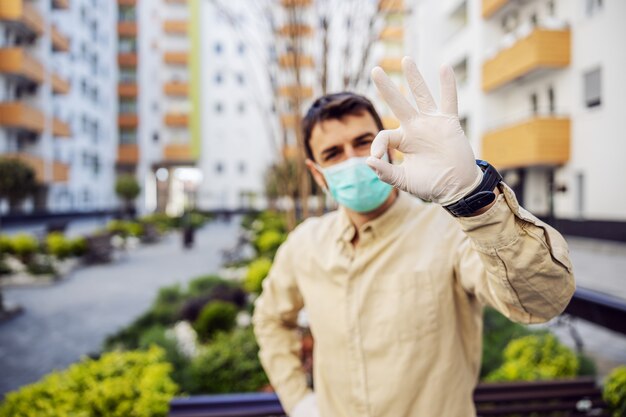 Hombre en traje protector con máscara mostrando los pulgares hacia arriba, caso de infección de virus, contaminación de gérmenes o bacterias. Prevención de infecciones y control de epidemias.