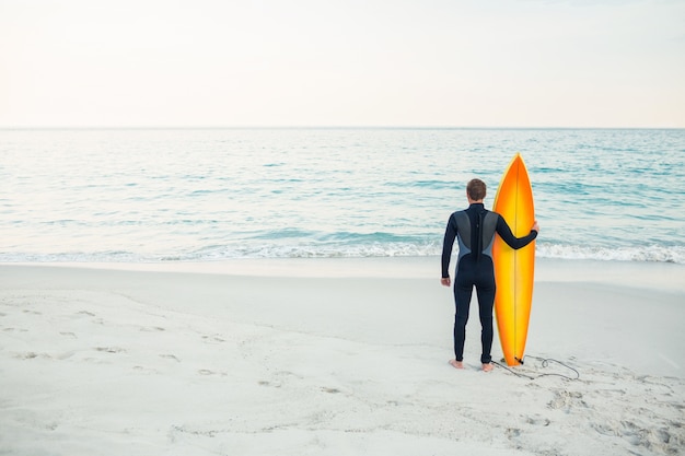 Hombre en traje con una tabla de surf en un día soleado