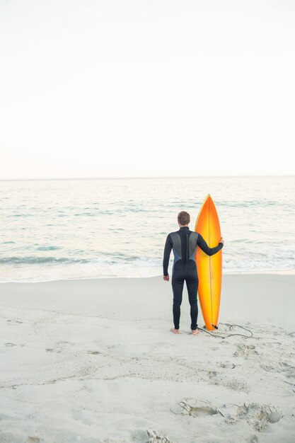 Hombre en traje con una tabla de surf en un día soleado