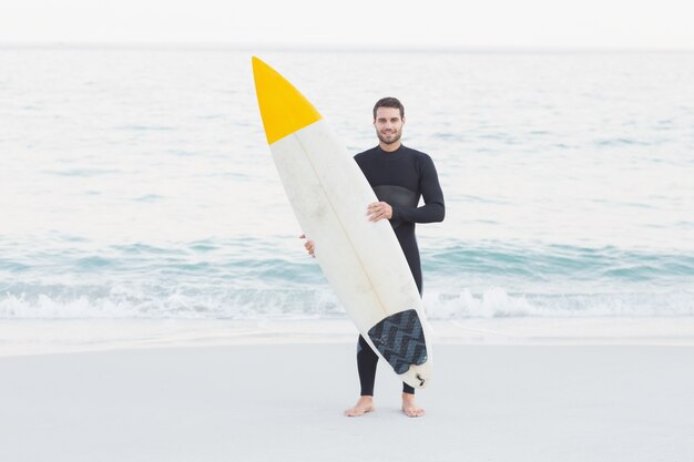 Hombre en traje con una tabla de surf en un día soleado