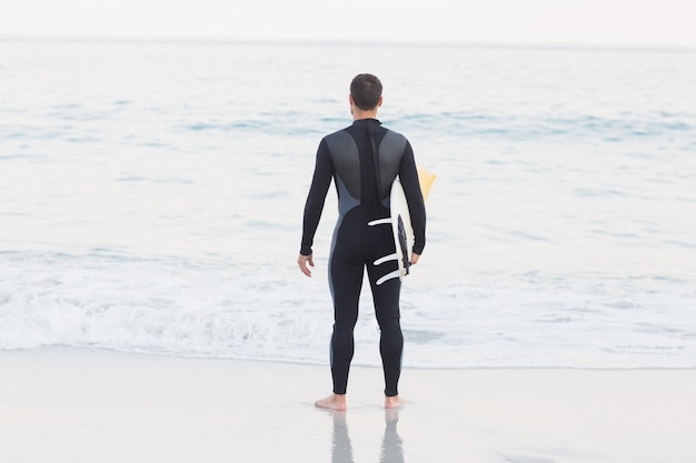 Foto hombre en traje con una tabla de surf en un día soleado