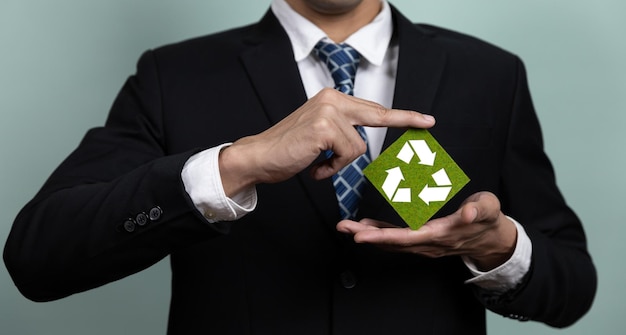 Un hombre con traje tiene un símbolo de reciclaje verde en sus manos.