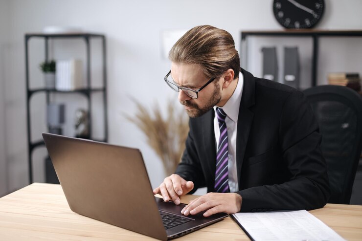 Hombre de traje trabajando en una laptop en la oficina