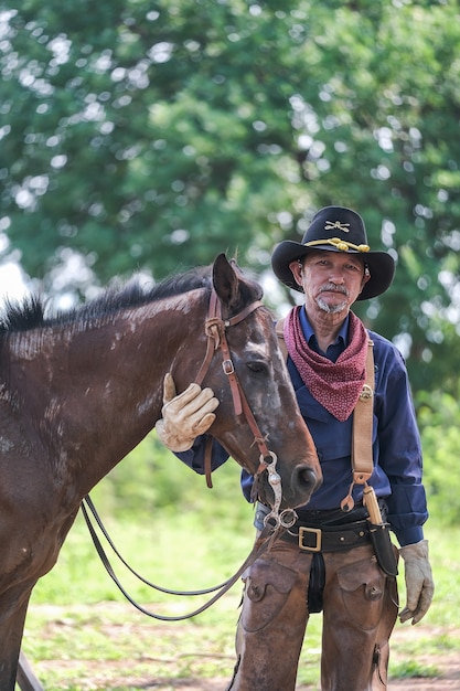 Un hombre en traje de vaquero con su caballo.