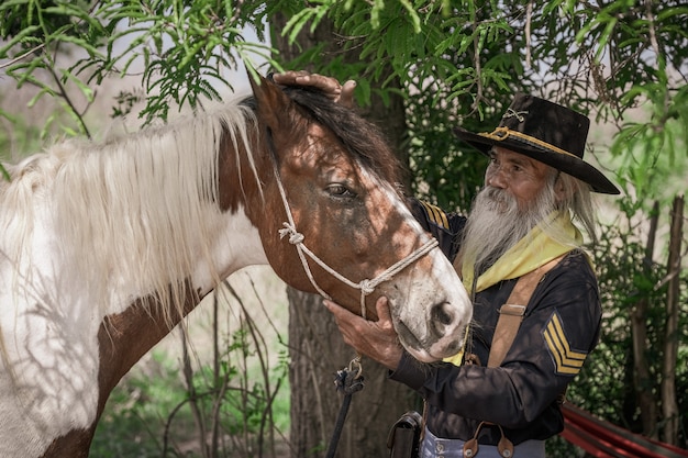 Un hombre en traje de vaquero con su caballo