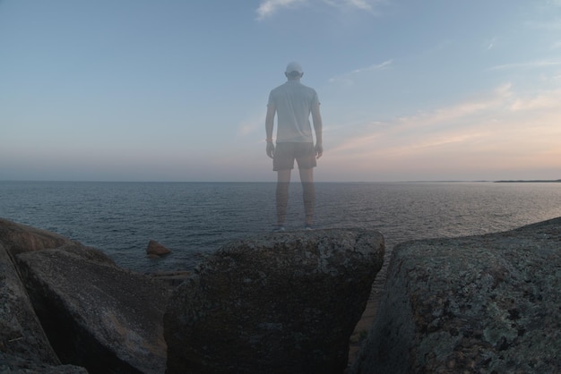 Un hombre transparente se encuentra en la costa rocosa Vista posterior