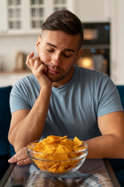 Hombre con trastorno alimentario tratando de comer patatas fritas