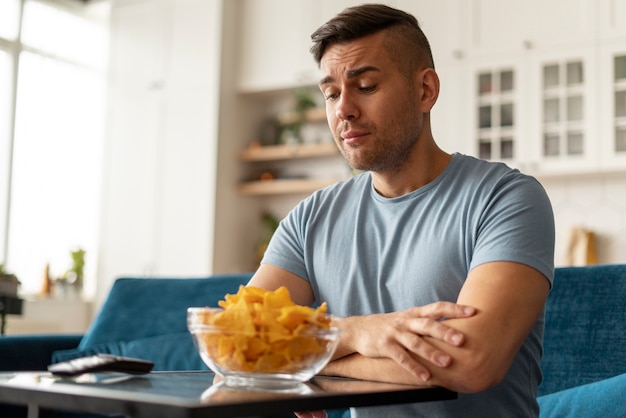 Foto hombre con trastorno alimentario tratando de comer patatas fritas