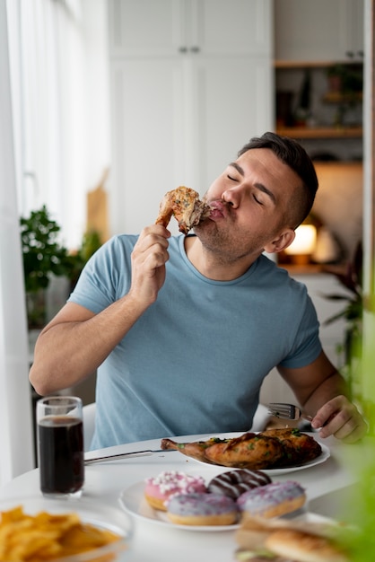 Foto hombre con trastorno alimentario tratando de comer pollo