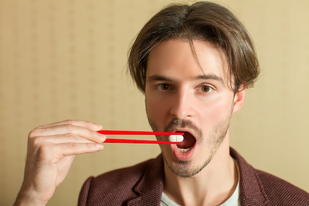 Hombre tratando de comer tableta con palillos.