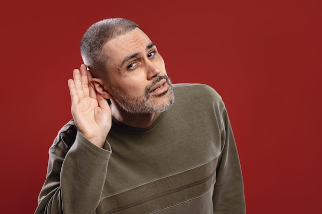 Foto hombre tratando de escuchar algo y poniendo su mano cerca de su oreja