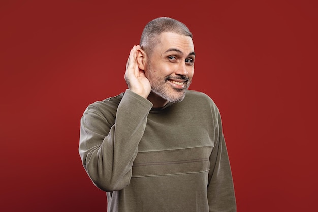 Foto hombre tratando de escuchar algo y poniendo su mano cerca de su oreja