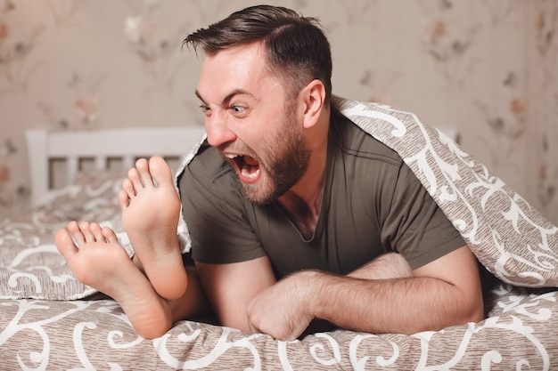 Hombre tratando de morder los pies de la mujer en la cama