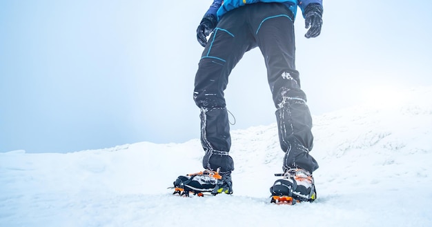 Hombre trekking montaña nevada con crampones para nieve profunda