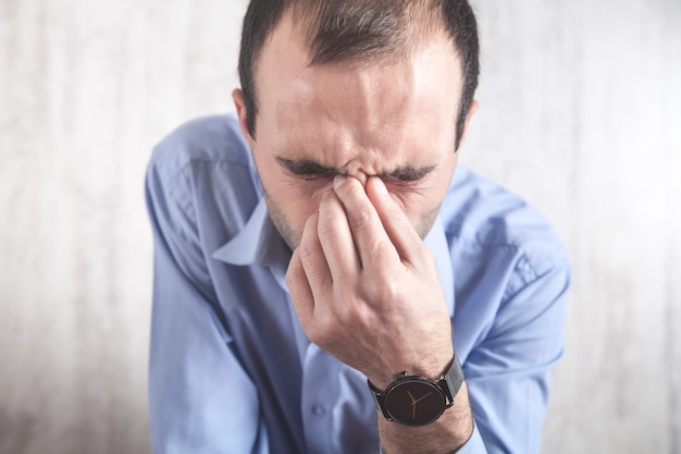 Hombre triste caucásico tapándose la nariz. Dolor de sinusitis