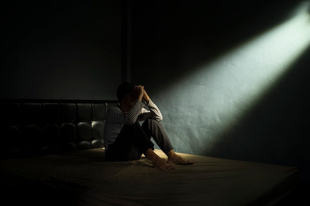 Foto hombre triste en el cuarto oscuro