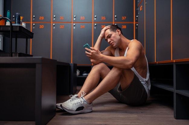 Hombre triste infeliz mirando su teléfono inteligente