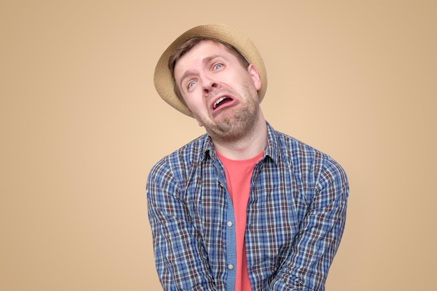 Hombre triste con sombrero de verano que parece molesto listo para llorar con una expresión facial desesperada