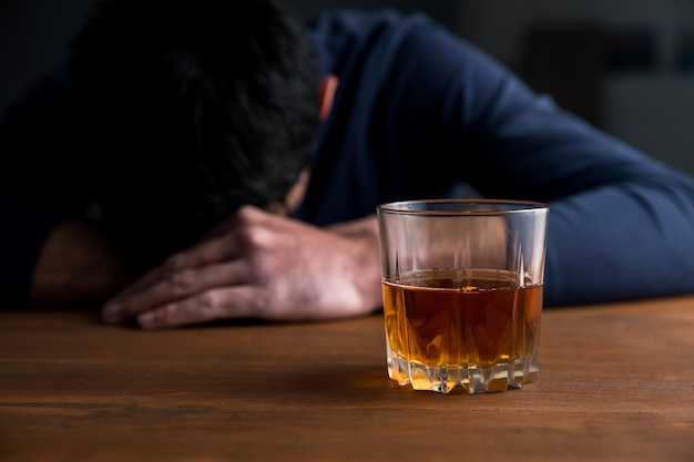 Foto hombre triste con vaso de whisky