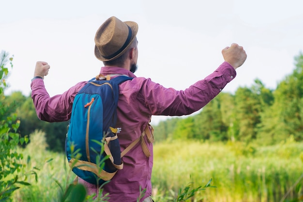 Hombre turista se encuentra en la orilla del lago con una mochila para viajar.