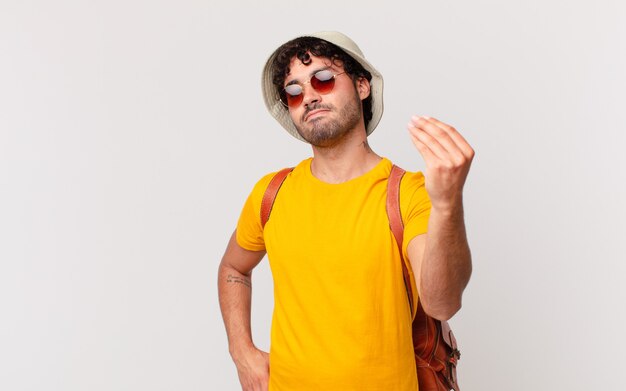 Hombre turista hispano haciendo capice o gesto de dinero, ¡diciéndole que pague sus deudas!