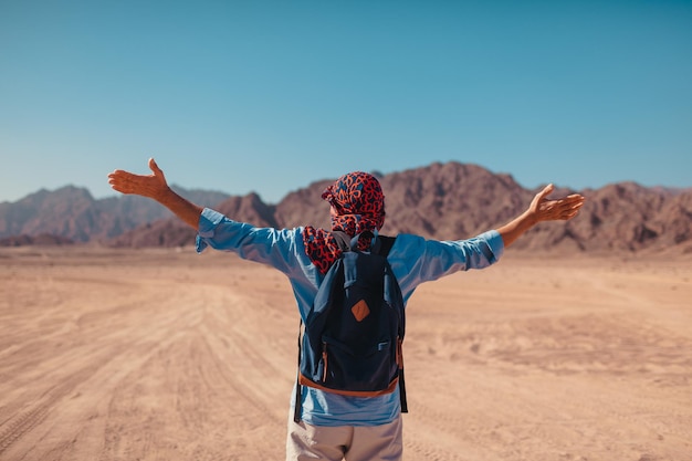 Foto hombre turista con mochila brazos levantados sintiéndose feliz y libre en el desierto del sinaí y las montañas viajero admirando el paisaje vacaciones de verano