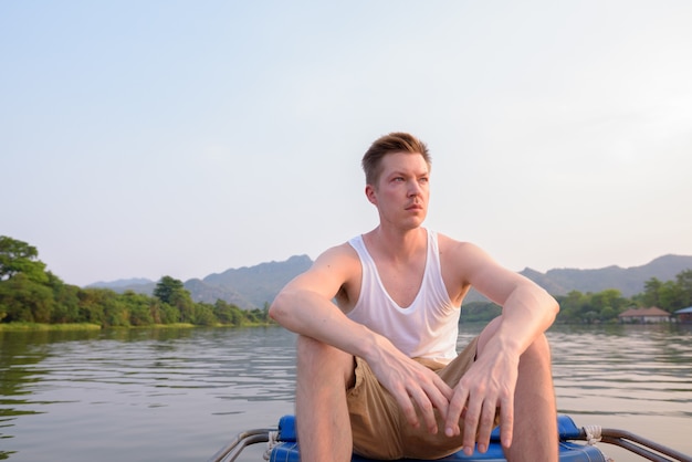 Hombre turista sentado en el barco mientras tiene vacaciones en Tailandia