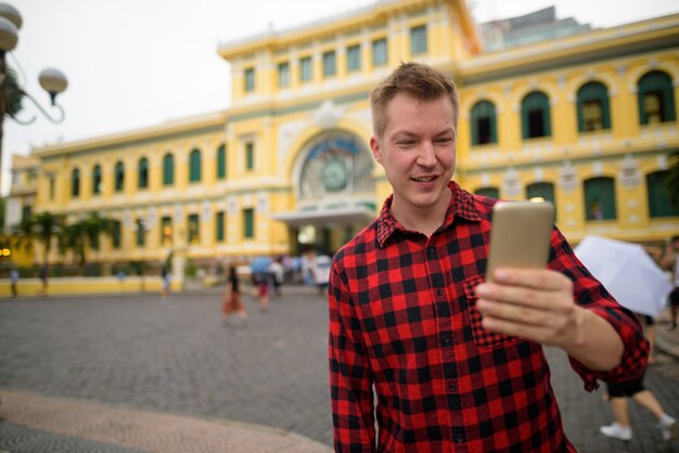 Hombre turista con teléfono delante de la Oficina Central de Correos de Saigón