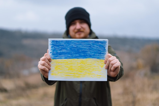 Hombre ucraniano sostiene una bandera pintada de la guerra de Ucrania de Rusia contra Ucrania