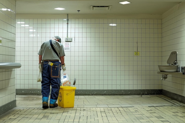 Un hombre con un uniforme azul está limpiando un baño