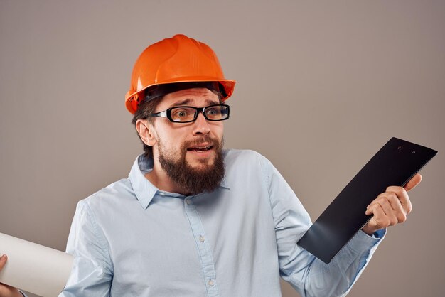 Hombre con uniforme de construcción casco naranja dibujos documentos de trabajo servicios foto de alta calidad