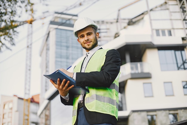 Hombre en uniforme de constructor sosteniendo mayores. Mirando el plan de construcción