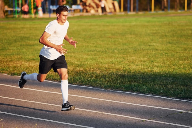 Hombre en uniforme deportivo corriendo en la pista durante el día