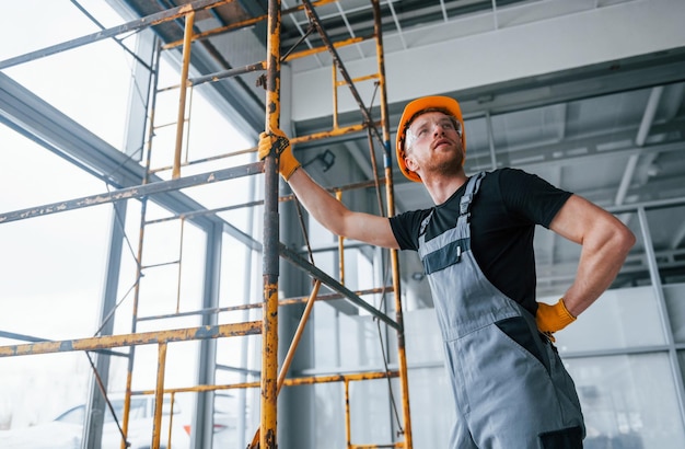 El hombre en uniforme gris trabaja con la construcción en interiores en una gran oficina moderna durante el día