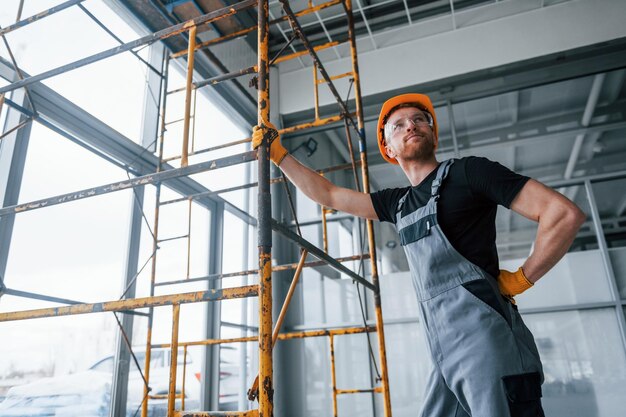 El hombre en uniforme gris trabaja con la construcción en interiores en una gran oficina moderna durante el día