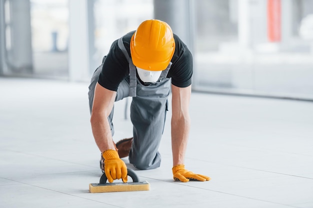 El hombre con uniforme gris trabaja en el interior de una gran oficina moderna durante el día