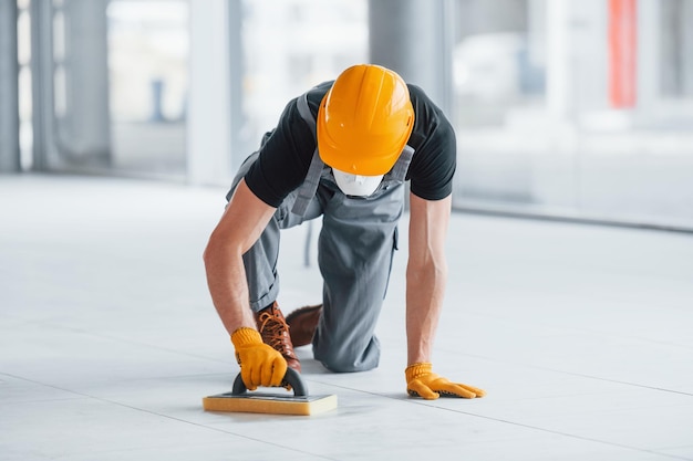 El hombre con uniforme gris trabaja en el interior de una gran oficina moderna durante el día