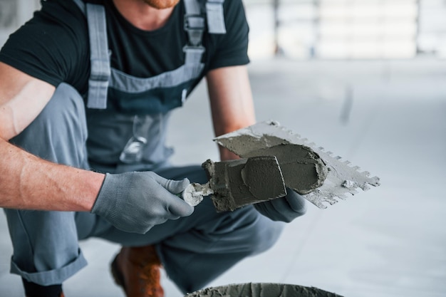 El hombre en uniforme gris trabaja con placa en interiores en una gran oficina moderna durante el día