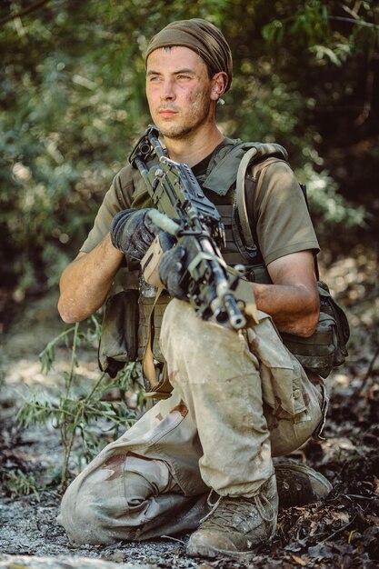 Hombre en uniforme militar con ametralladora en el bosque guerra militar y concepto de personas