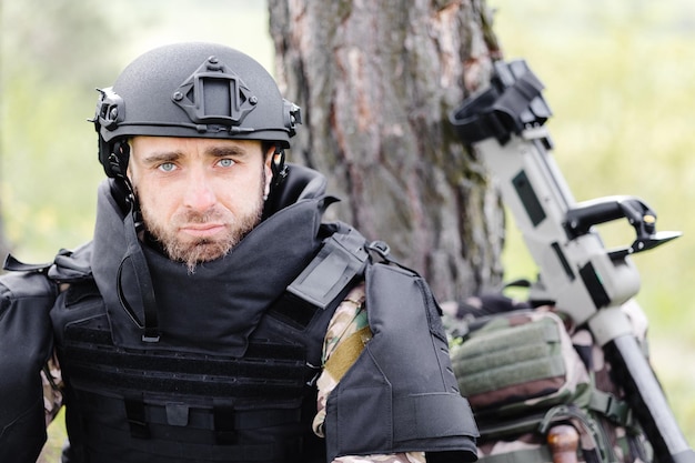 Un hombre con uniforme militar y un chaleco antibalas se sienta en