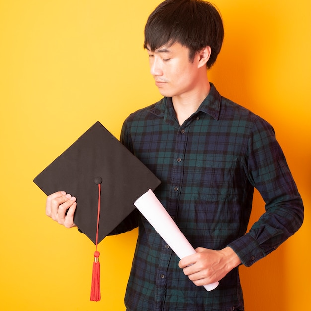 El hombre de la Universidad está feliz con la graduación sobre fondo amarillo