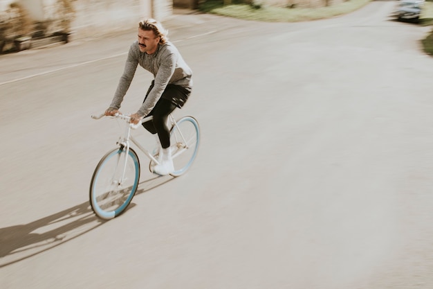 Hombre urbano con bigote en bicicleta por las calles