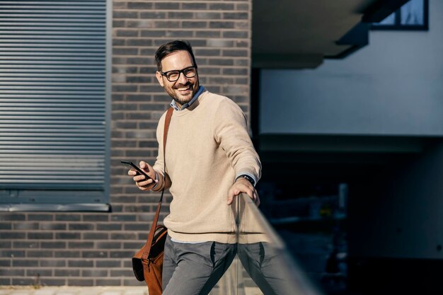 Un hombre urbano feliz usa un teléfono afuera