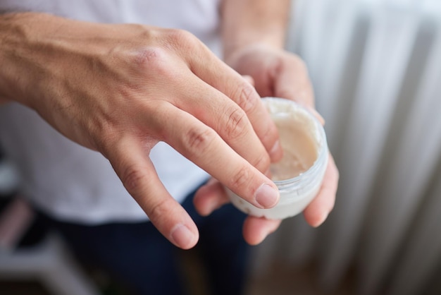 El hombre usa crema de manos para cerrar las manos de los hombres tonificados