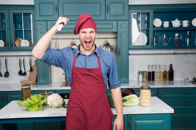 El hombre usa un cuchillo de cerámica afilado. Herramienta profesional cuchillo afilado. Chef elige herramientas profesionales. Utensilios y herramientas de cocina. El chef sostiene la herramienta cuchillo lista para cocinar. Delantal de desgaste de chef hombre cocinando en la cocina.