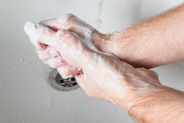 El hombre usa jabón y lavarse las manos debajo del grifo de agua. Concepto de higiene detalle de la mano.