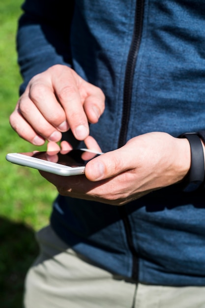 Un hombre usa un teléfono inteligente al aire libre.