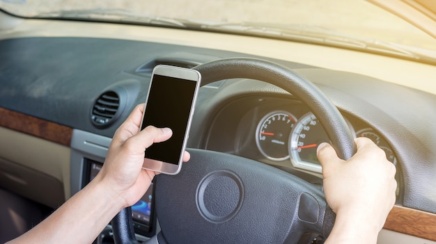 El hombre usa un teléfono inteligente en su coche.